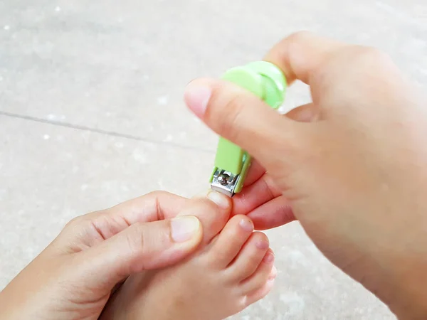 Primer plano madre asiática cortar las uñas de los pies del bebé con corte de uñas o cortauñas — Foto de Stock