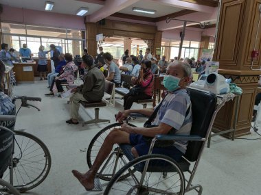 CHIANG RAI, THAILAND - 23 Mart 2020 'de Chiang Rai, Tayland' da Covid-19 virüsünün yayılması sırasında Phan hastanesinde tekerlekli sandalyede oturan kimliği belirsiz Asyalı erkek hasta.