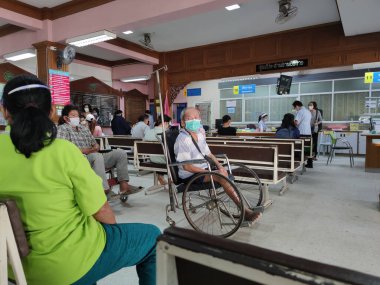 CHIANG RAI, THAILAND - 23 Mart 2020 'de Chiang Rai, Tayland' da Covid-19 virüsünün yayılması sırasında Phan hastanesinde hijyenik maske kullanan tanımlanamayan eski Asyalı hasta.