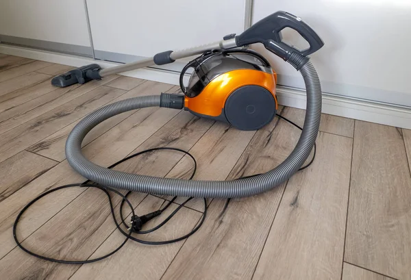 Tahta zeminde ev temizliği için elektrikli süpürge. Seçici odaklanma. Yatay yönelim.