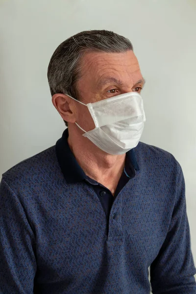 An adult elderly man in a medical mask because of a coronavirus.