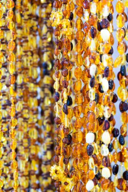 Doğal veya taklit kehribardan yapılmış ürünler. Kadın mücevherleri, boncuklar. Dikey oryantasyon. Seçici odaklanma. Maviydi. Önden görünüm.