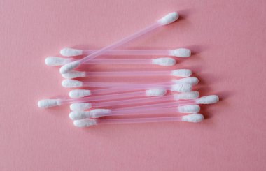 Temizlik için pamuk çubukları ve pembe arka planda plastik ve doğal pamuk lifinden yapılmış makyaj malzemesi. Plastiksiz, kozmetik konsepti. Kapatın. Yukarıdan görüntüle. 