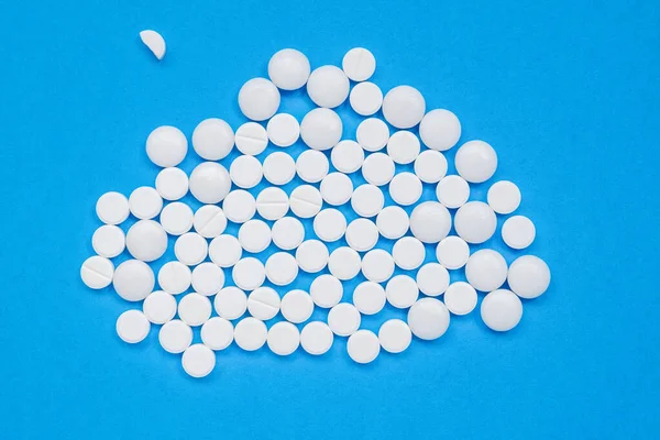 Muitas pílulas brancas em um fundo azul. — Fotografia de Stock