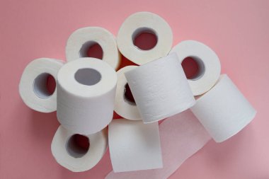 Pembe arka planda bir sürü beyaz tuvalet kağıdı var. Panik, covid-19 konsepti.