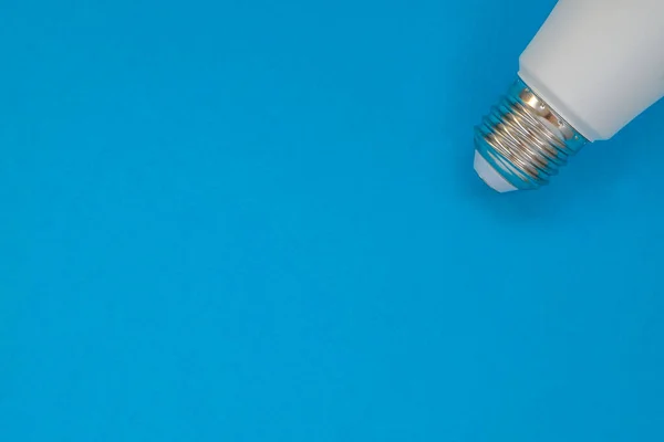 Copy space for your text on a blue background with a pits of matte energy-saving light bulbs in the corner. Horizontal orientation.