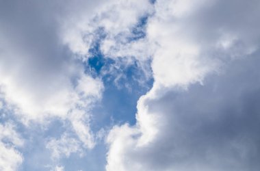 Parlak mavi gökyüzü güneşli bir günde beyaz kümülüs bulutlarının arasından bakar. Yatay oryantasyon. Seçici odak.