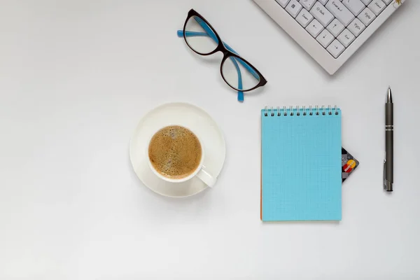 Teclado, xícara de café, caneta, óculos e bloco de notas do qual você pode ver o canto do cartão de crédito — Fotografia de Stock