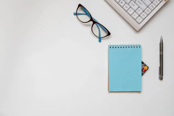 Eine Tastatur, ein automatischer Stift, eine Brille und ein Notizbuch, von dem aus man die Kreditkartenecke sehen kann — Stockfoto