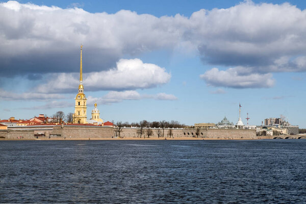 View across the River Neva to the Petropavlovsk fortress from the arrow of Vasilyevsky Island on a sunny day with beautiful clouds in the sky in early spring or late autumn. St. Petersburg, Russia.