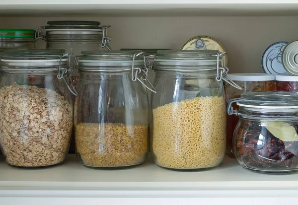 Separation in a kitchen cupboard or pantry with cereals and canned goods — Stock Photo, Image