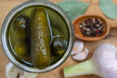 Cam bir kavanozda turşu ve tahta bir yüzeye yerleştirilmiş turşu..