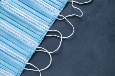 Coronavirus, COVID-19 salgını. Koronavirüse karşı korunmak için antiviral tıbbi maske. Cerrahi koruyucu maske. Siyah arka planda tıbbi yüz maskesi. Ev konseptinde kal. Boşluğu kopyala.