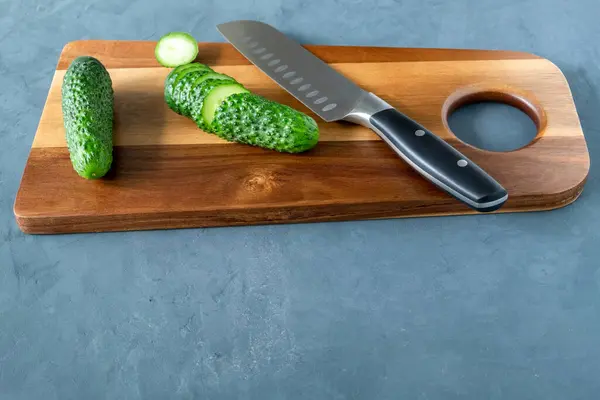 Pepino fresco en rodajas y un cuchillo en una tabla de cortar — Foto de Stock