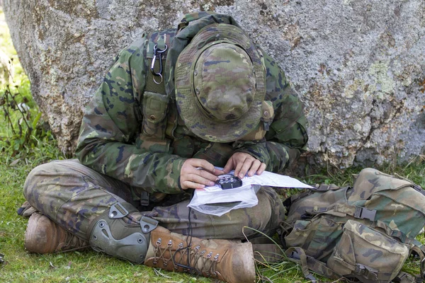 Soldado del ejército terrestre miró un mapa con una brújula para orientar Imagen de archivo