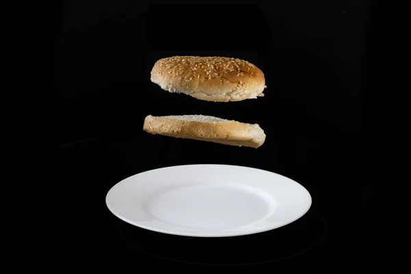 Siyah arka planı olan bir tabakta hamburger ekmeği