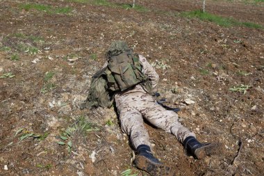 Asker tüm kamuflaj teçhizatlarıyla yerde yatıyor.