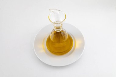 Beyaz arka planda ekstra bakire yağı olan beyaz bir tabakta cam yağ tenekesi.
