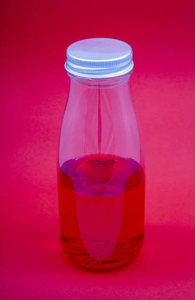 Kırmızı arka planı olan şeffaf bir tencerede kırmızı içecek.