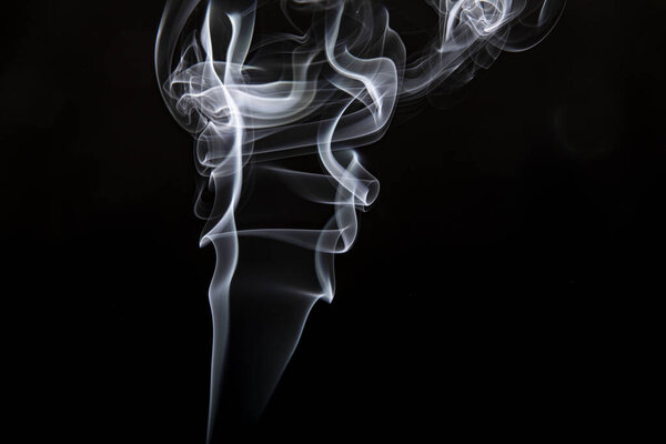 Swirls of white incense smoke on a black background