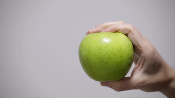 ruka bere zelené jablko na bílém pozadí