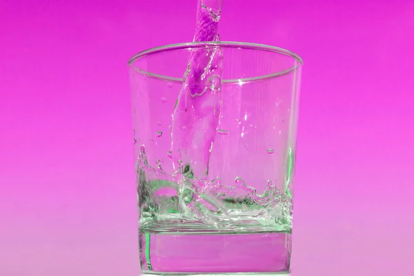 水杯充满了粉红色背景的水杯 — 图库照片