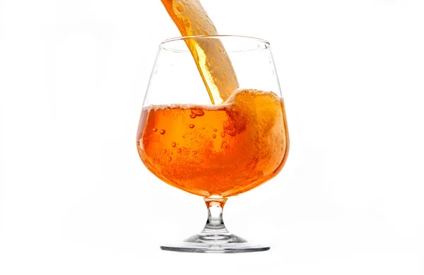 Beyaz arka planı olan kristal bir bardağa bira dolduruyor.