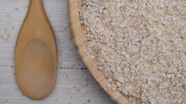 Beyaz ahşap bir arka planda, tahta bir tabakta yulaf ezmesi ve yulaf ezmesi. 