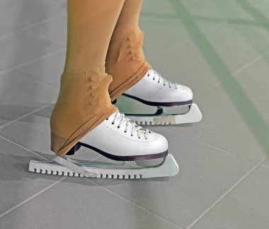 Antrenmandan önce ya da sonra artistik patinaj yapan kadın bacakları. Örtülü bıçak. Deri taytlar botların arkasına gerilmiş. En yakın bacağa odaklan.