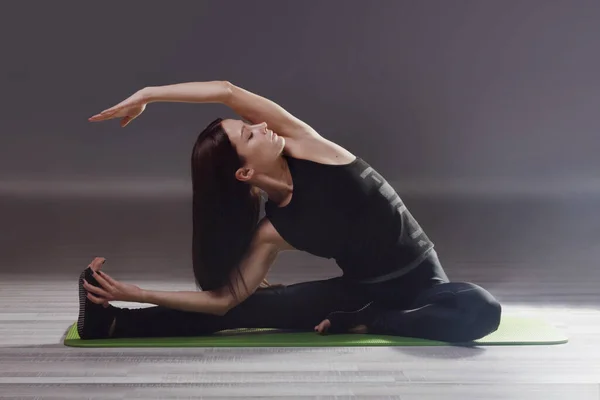 Ung kvinna som utövar yoga på grön matta Royaltyfria Stockbilder