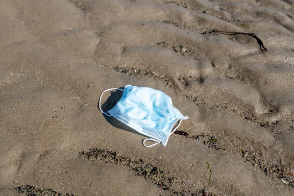 浜に捨てられた外科用マスク — ストック写真