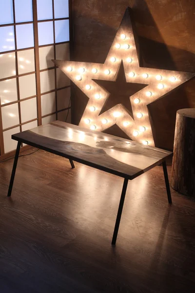 Wood and epoxy table with star lamp in wooden interior