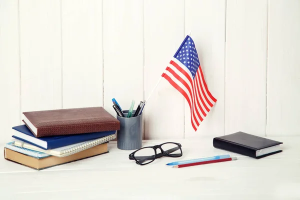 Books, notebooks, glasses and the US flag on the desk. English language learning. Flag the United States of America.