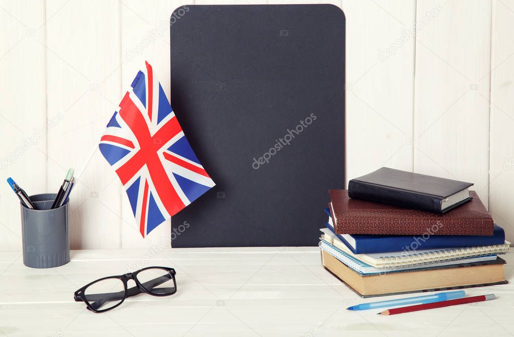 Books, notebooks, glasses and the Great Britain flag on the desk. English language learning.