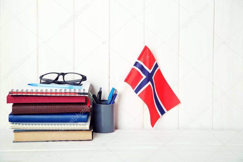 Education in Norway. Books, notebooks, textbooks, glasses, a flag on a wooden table.