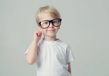 Gözlüklü sarışın küçük çocuk bir dilek yapar ve kendini kulak tarafından tutar.