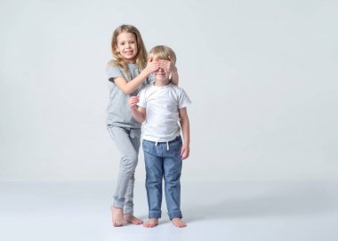 Çocuklar, kardeşi ve kız kardeşi üzerinde hafif bir arka plan ayakta. Küçük kız çocuğu için gözleri kapalı. Sürpriz.