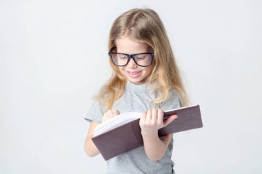 Onun elinde bir kitapla küçük kız bardaklarda.