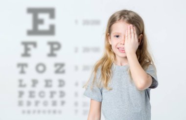 Küçük kız arka plan üzerinde test göz görme testi tabloları. Doktor Pediatrik göz doktoru ziyaret.