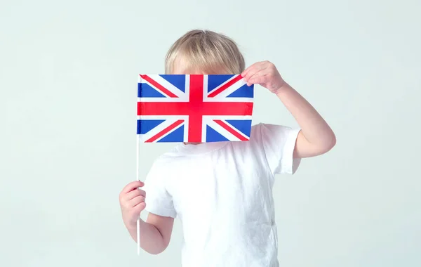 Learn English! The boy hid his face behind the flag of Great Britain.