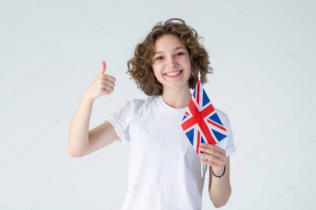 Like it! Curly young woman with UK flag showing thumb up, standing on white background. Learning English is cool.