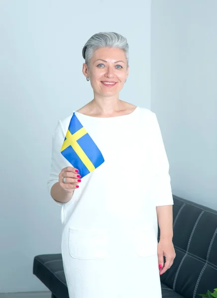 有瑞典国旗的成熟女人站在办公室 头发灰白的短发女 — 图库照片