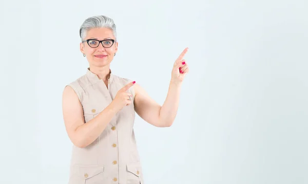 Happy Middle Aged Woman Glasses Points Fingers Right Standing Light — Stock Photo, Image