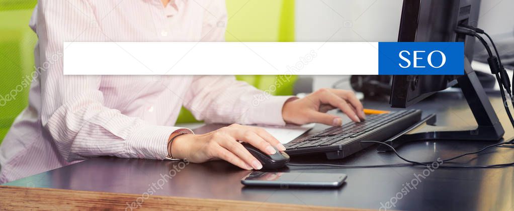 SEO optimization, search bar on the background of hands typing on a computer keyboard.