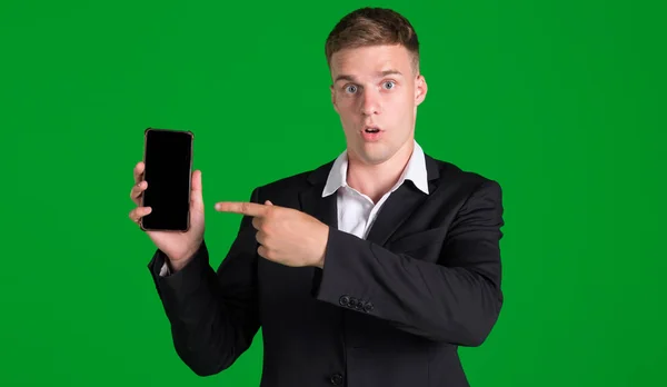 Surprised Man Points Finger Smartphone Blank Screen Isolated Green Background — Stock Photo, Image