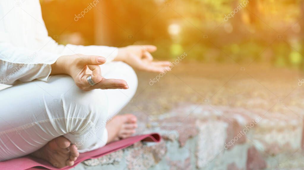 Close up of female hands. Woman is practicing yoga and meditation. Relax in nature. Woman during retreat classes.