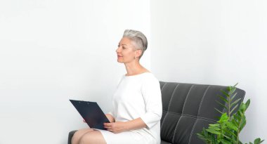 Ofisteki koltukta oturan olgun bir iş kadını. Başvuru formunu ya da sigorta belgelerini satış bürosundan doldurun.