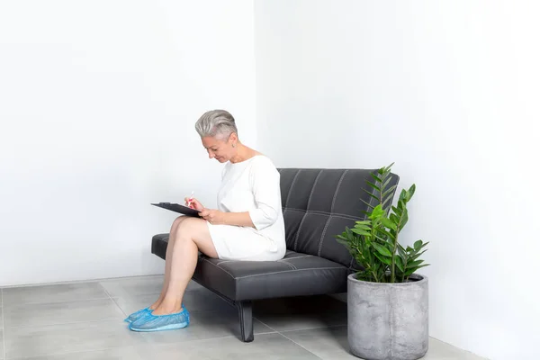 Mature Woman Filling Out Questionnaire While Sitting Sofa Clinic Reception — Stock Photo, Image