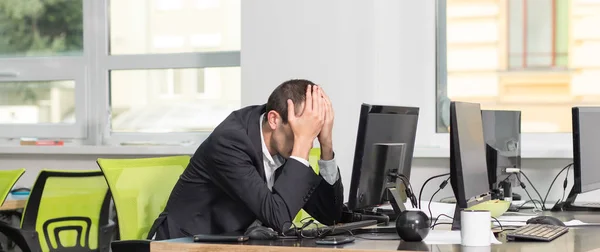 Portrait of sad and tired businessman in suit sitting with monitor computer in office room. Frustrated business man.