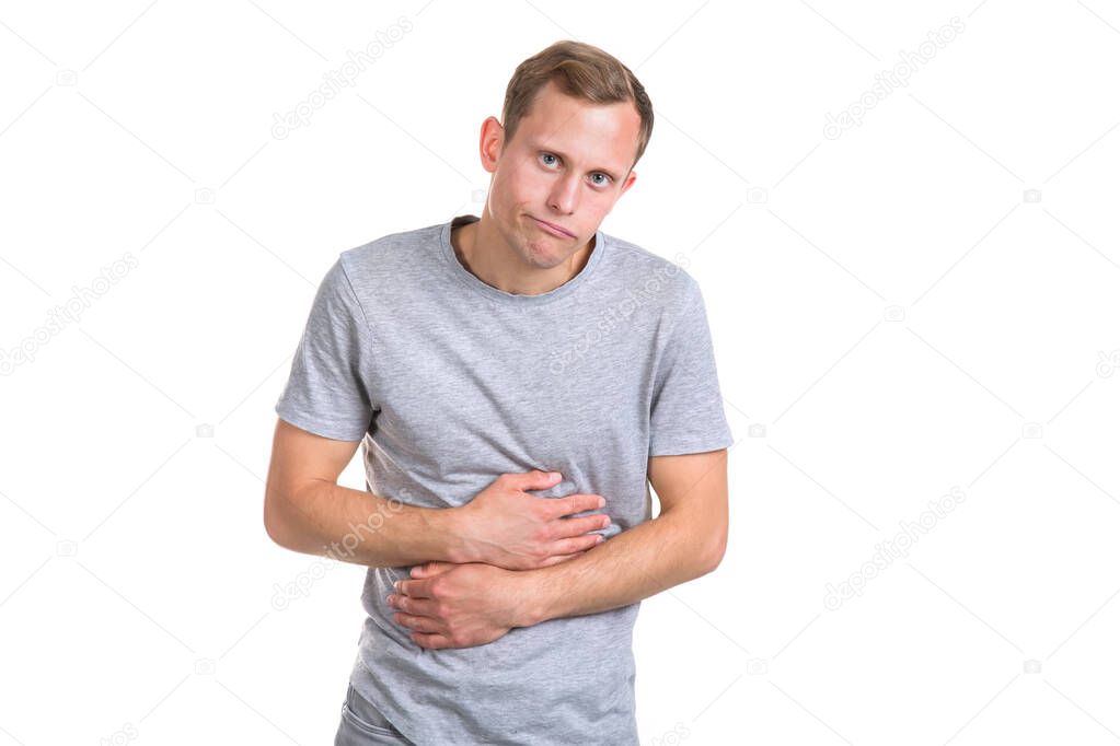 Sick young man holding his belly with his hands, isolated on a white background. Pain in the stomach, constipation in the intestines.